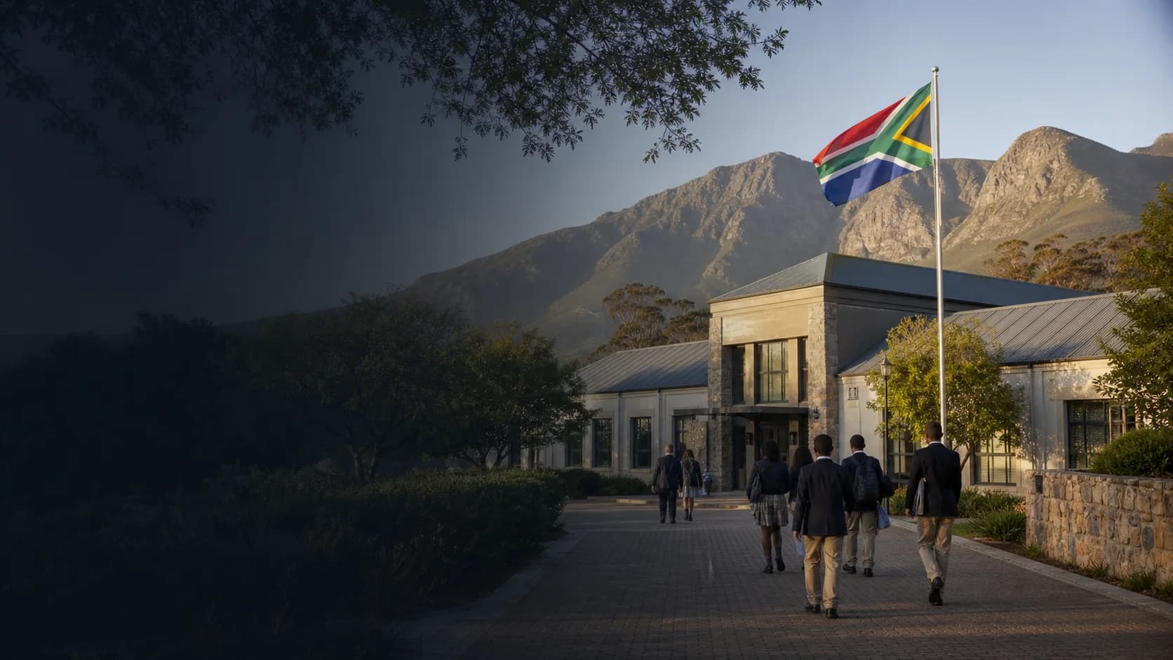 South African learners approaching a school where the South African flag is flying